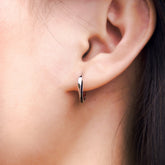 Fine jewellery, silver jewellery, hypoallergenic, tarnish-free, close-up front view of a Pair of silver glazed black hoop earrings worn on a person's ear
